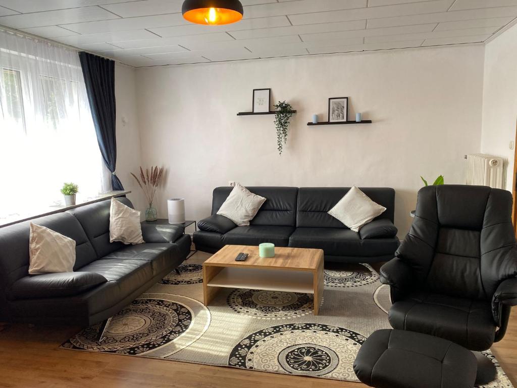 a living room with black leather couches and a coffee table at Ferienhaus SüMeer in Wilhelmshaven