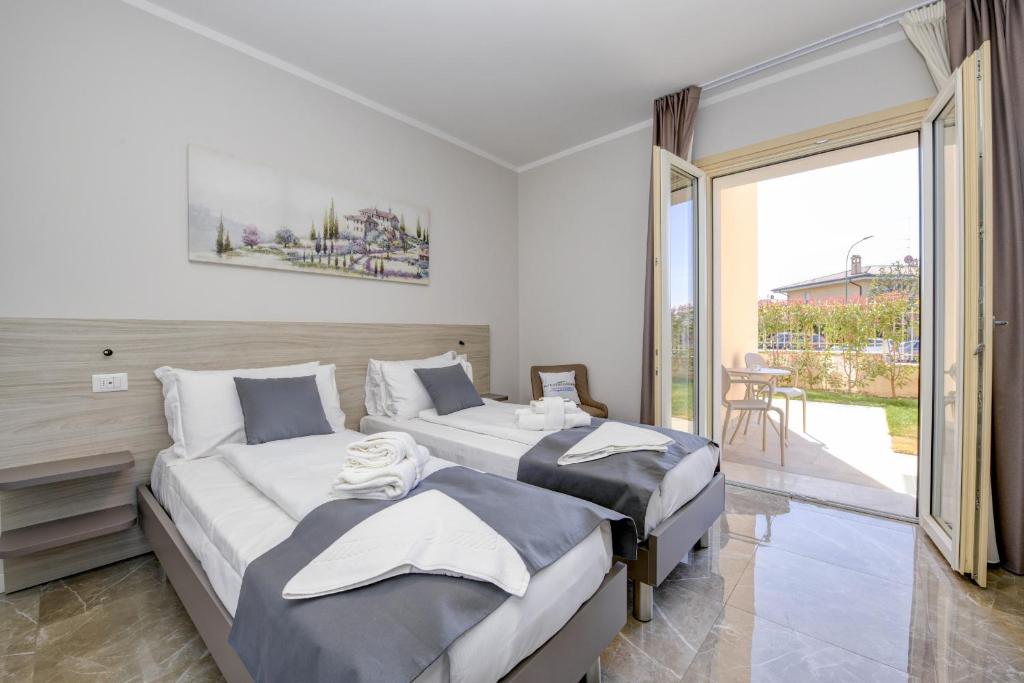 a bedroom with two beds and a sliding glass door at Ranalli Palace in Peschiera del Garda
