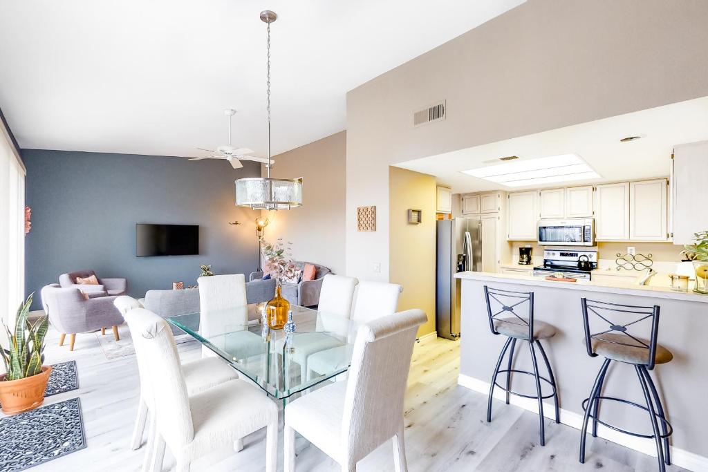 uma cozinha e sala de estar com uma mesa de vidro e cadeiras em Laurel Valley Lounger Permit# 068,408 em La Quinta