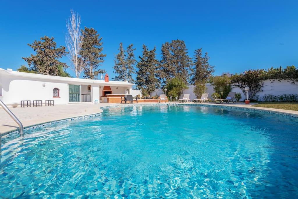 a swimming pool with blue water in front of a house at villa des jasmins in Tunis