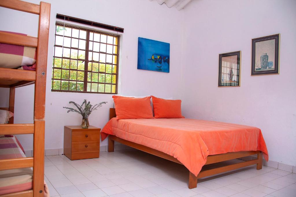 una camera da letto con un letto con lenzuola arancioni e una scala di Casa Hudié Campestre a Cachipay