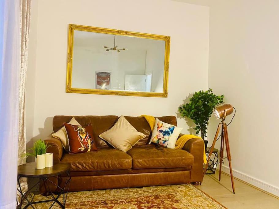 a brown couch in a living room with a mirror at Sanctuary Spaces at The Shard with private parking in London