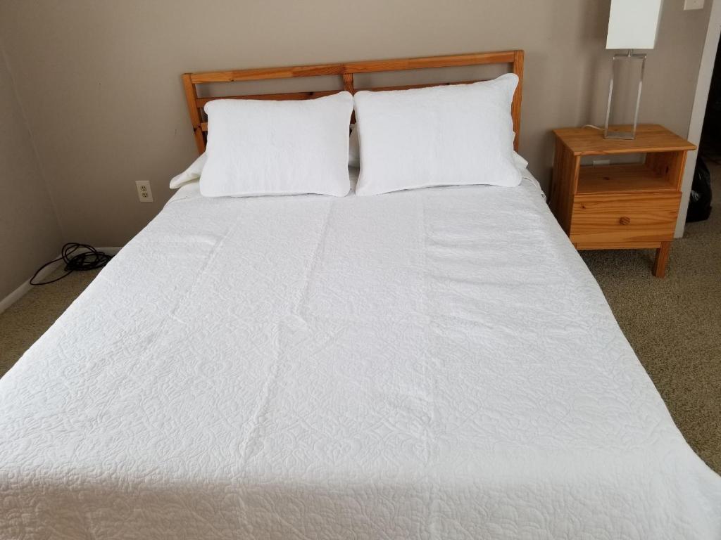 1 cama blanca con 2 almohadas y una mesita de noche en The Point - On Gull Lake, en Brainerd