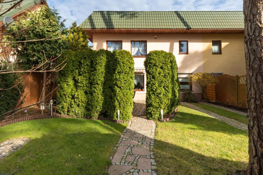 a house with a hedge in front of a yard at Holiday House "Słoneczna" with Garden by Renters in Łukęcin