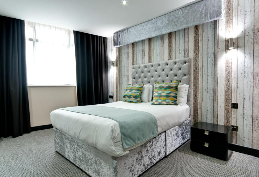 um quarto com uma cama grande e uma grande cabeceira. em Print Works Hotel em Liverpool