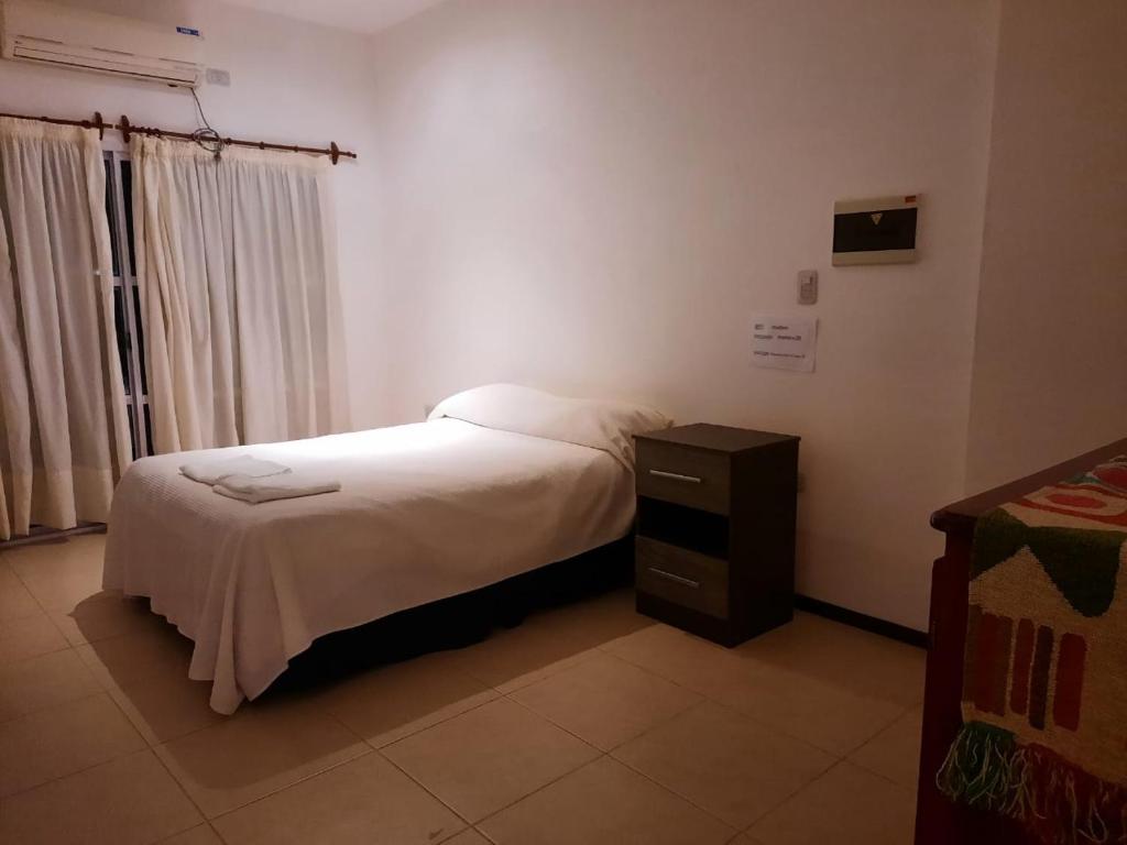 um pequeno quarto com uma cama e uma mesa de cabeceira em Loma Blanca em Libertador General San Martín