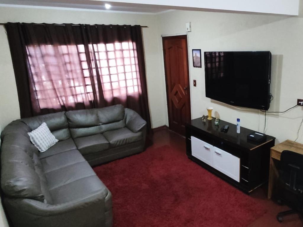a living room with a couch and a flat screen tv at Apt térreo com 3 qtos e 1 vaga in Poços de Caldas