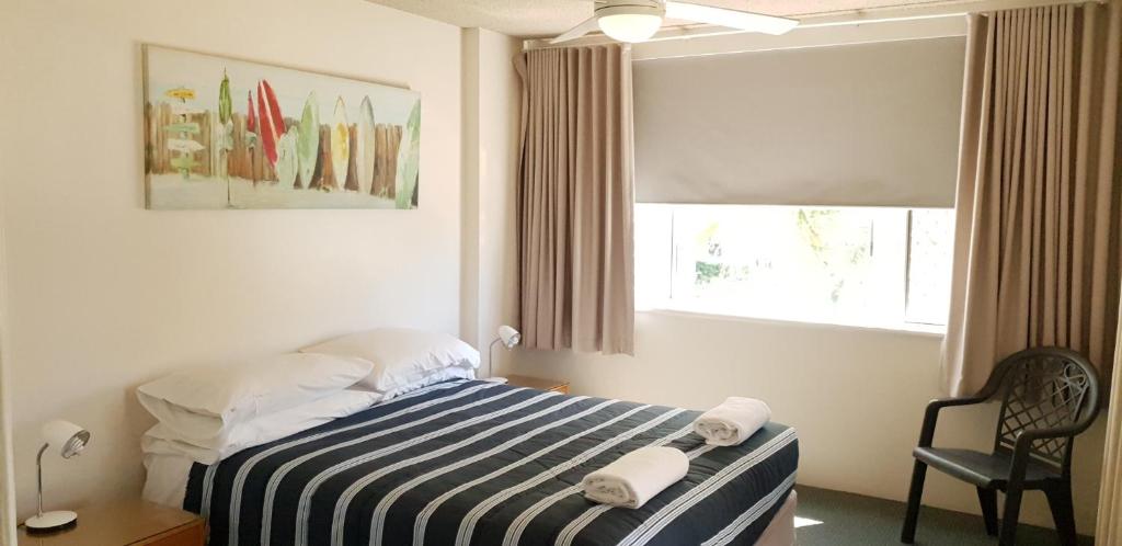 a bedroom with a bed with two towels on it at Wyuna Beachfront Holiday Apartments in Gold Coast