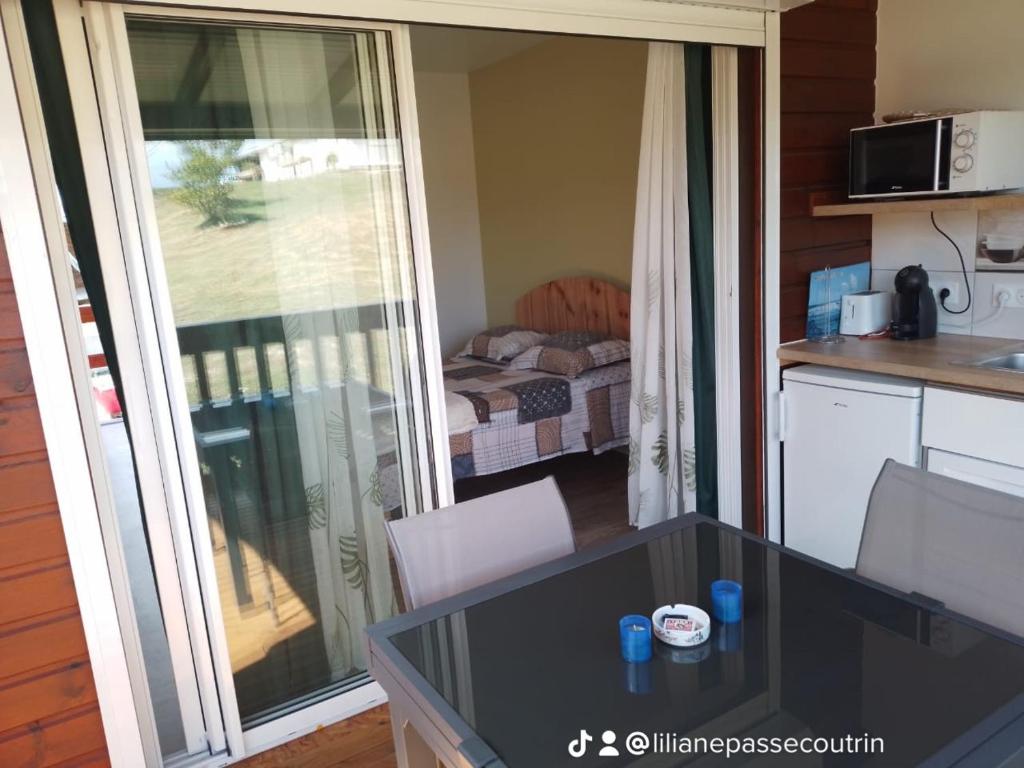 a kitchen with a table and a balcony with a bedroom at Depaysement total au coeur de la campagne de vacances ideales pour se ressourcer in Saint-Louis