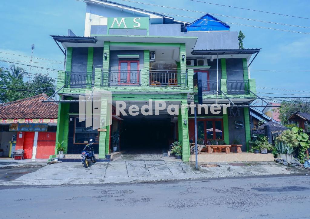 a green building with a red perimeter sign on it at MS Hotel Pangandaran Mitra RedDoorz in Pangandaran