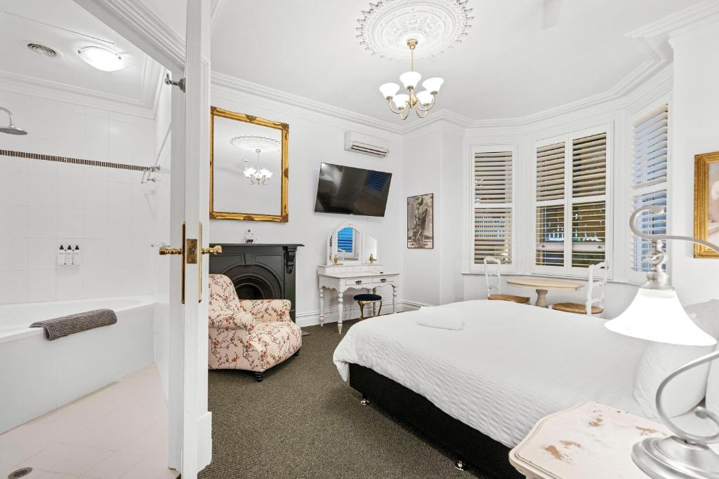 Accommodation in Fremantle في فريمانتل: غرفة نوم بيضاء مع سرير ومدفأة