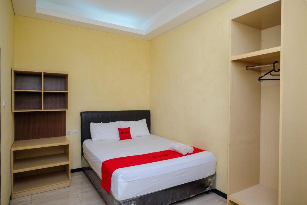 a small bedroom with a bed and shelves at RedDoorz near Taman Pantai Alam Indah Tegal in Tegal