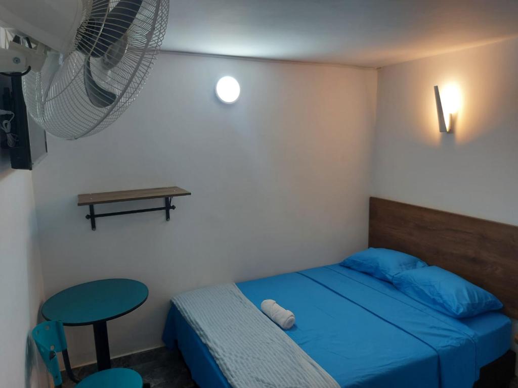 Dormitorio pequeño con cama azul y taburete en HOTEL DEPARTAMENTAL, en Ibagué