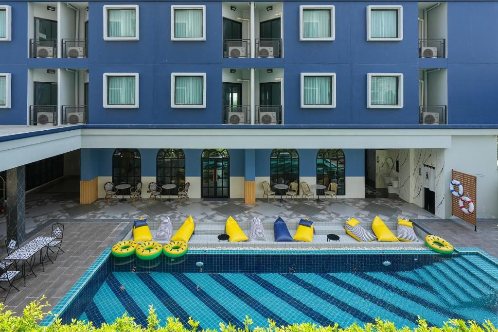 a hotel with a swimming pool in front of a building at Cozy Blu Suvarnabhumi in Samutprakarn