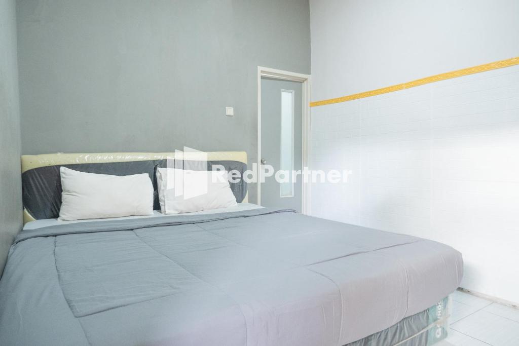 1 dormitorio con 1 cama con sábanas y almohadas blancas en Crown Residence near Tugu Yogyakarta Mitra RedDoorz, en Yogyakarta