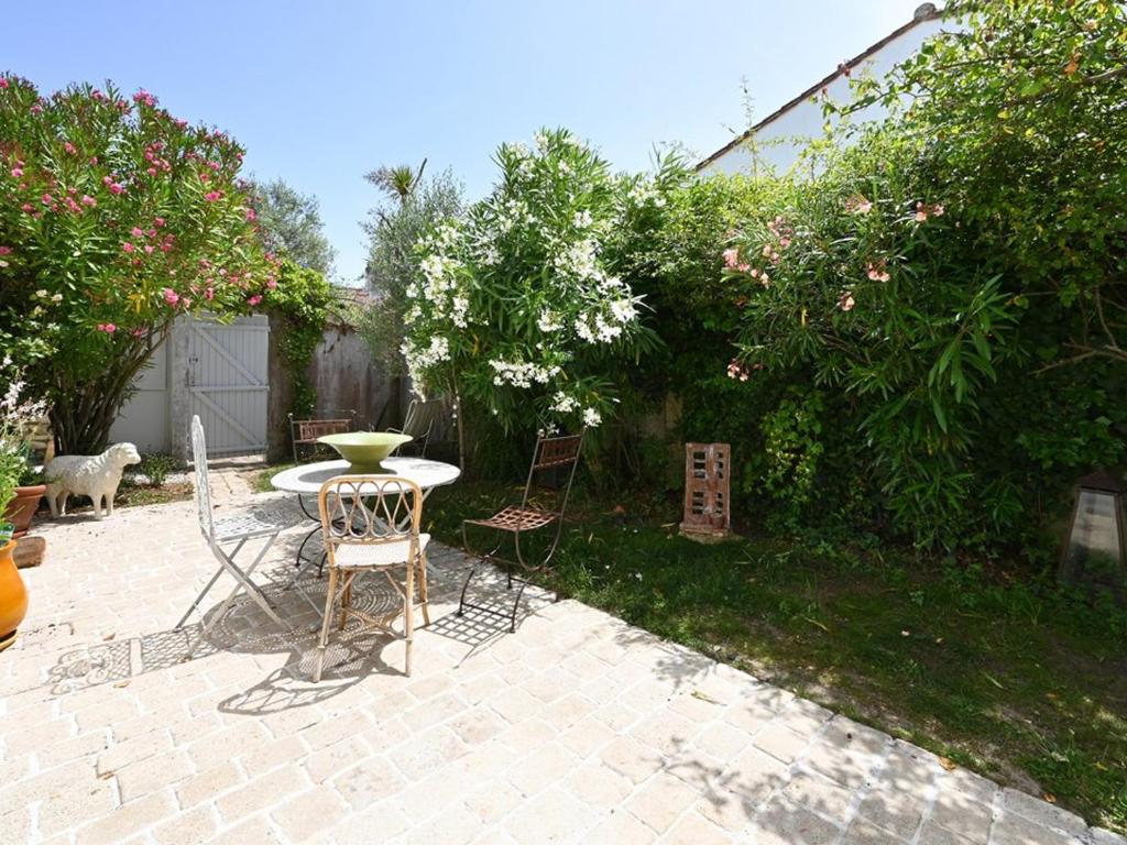 un patio con tavolo e sedie in un cortile di Maison Les Portes-en-Ré, 3 pièces, 4 personnes - FR-1-434-105 a Les Portes