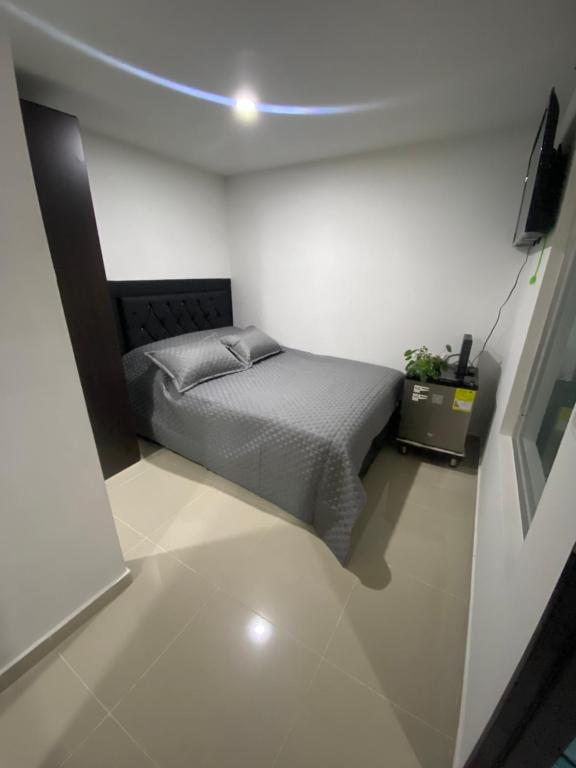 a bedroom with a bed in a white room at Apartaestudio de 1 habitación Disfruta Medellin in Medellín