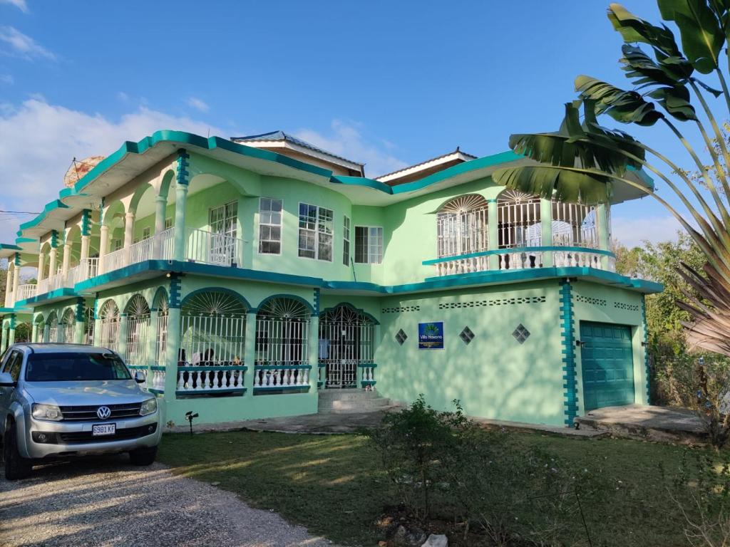 zielony dom z samochodem zaparkowanym przed nim w obiekcie Villa Havana Negril w Negril