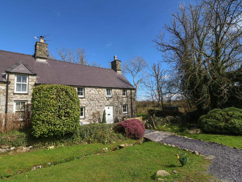 una vecchia casa in pietra con un cortile verde di Y Bwthyn Ty Du a Llannor