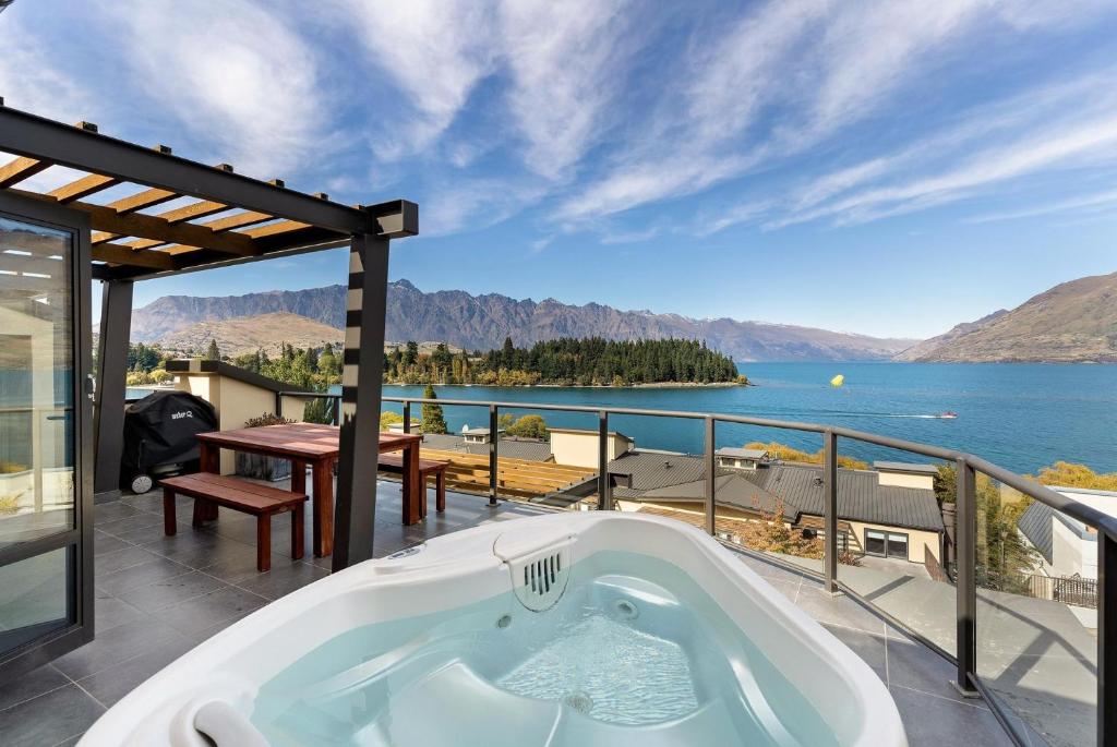 a bath tub on a balcony with a view of the water at Beacon Lakeside Luxury 908 - 3 Bedroom in Queenstown