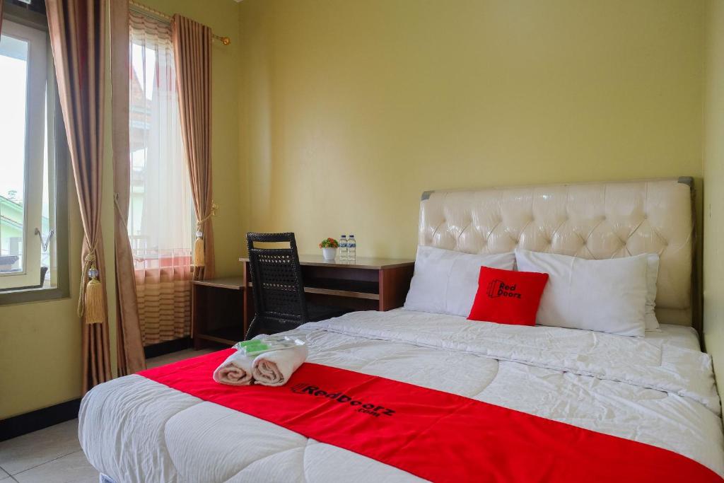 a bedroom with a large bed with two towels on it at RedDoorz Syariah near Taman Rekreasi Kalianget Wonosobo in Kalianget