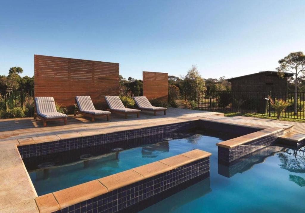 une piscine avec des chaises longues dans une cour arrière dans l'établissement The Nature Resort Villas Ramada Resort, à Cowes