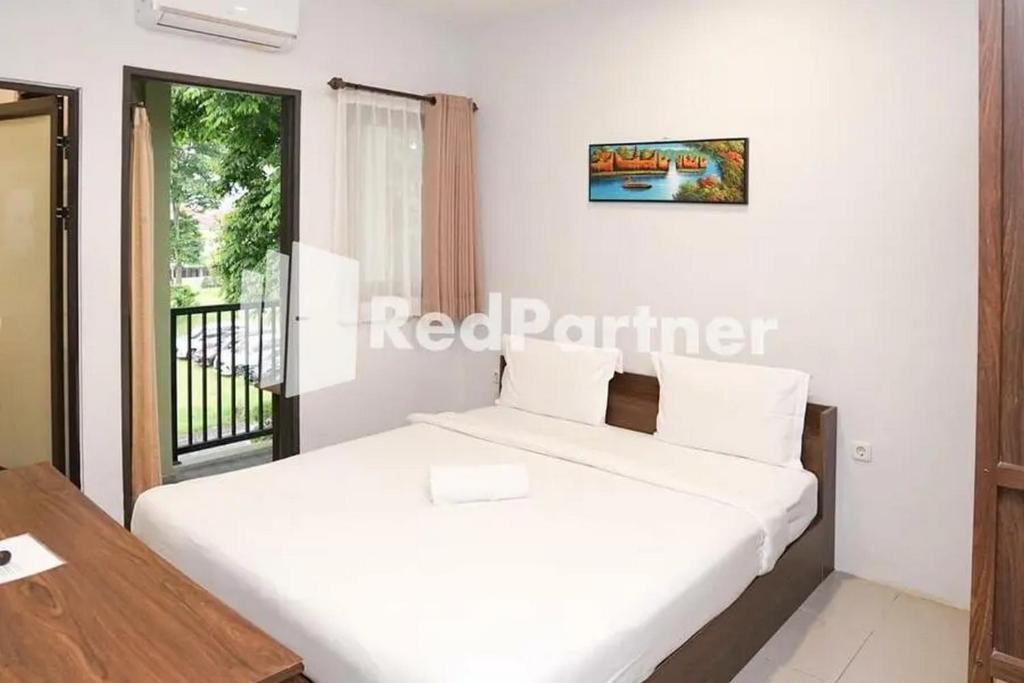a bedroom with a bed and a table and a window at Panorama İnn Residence Batu Mitra RedDoorz in Batu
