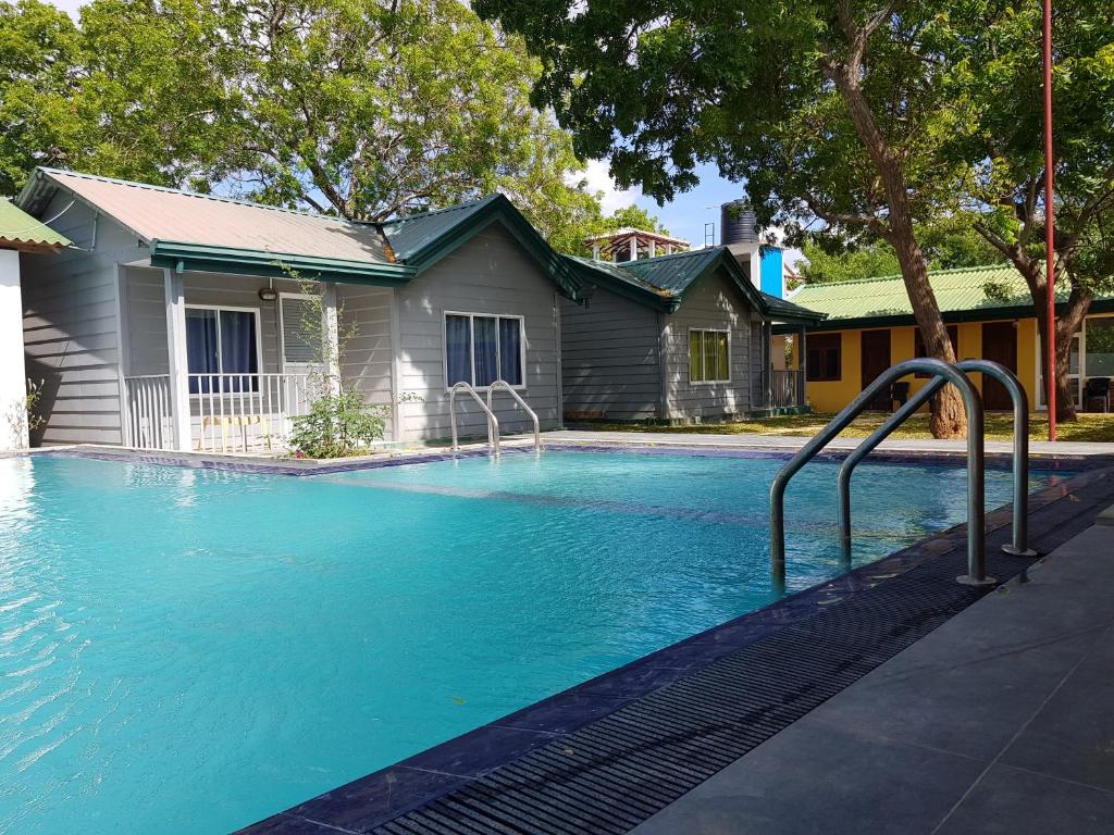 a swimming pool with blue water in front of a house at Triple Tree Cottage in Tissamaharama