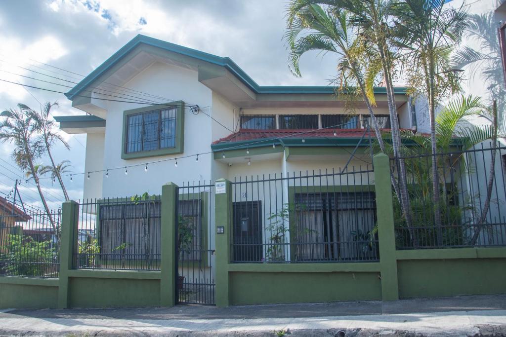 une maison blanche avec une clôture verte dans l'établissement Las Carmelas, Airport Juan Santamaría, Alajuela, San José, à Alajuela