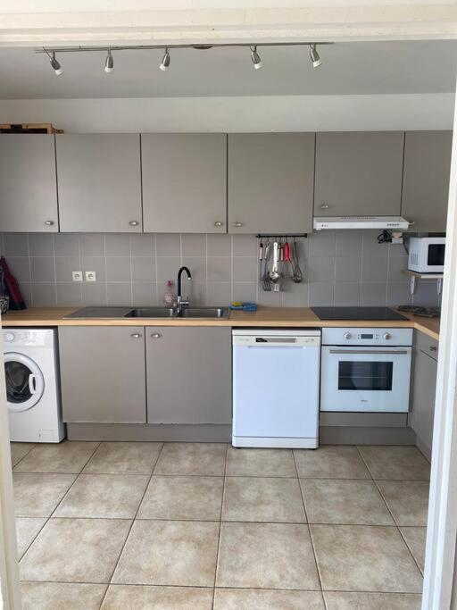 a kitchen with white cabinets and appliances in it at Maison Agréable Familiale in Saint-François