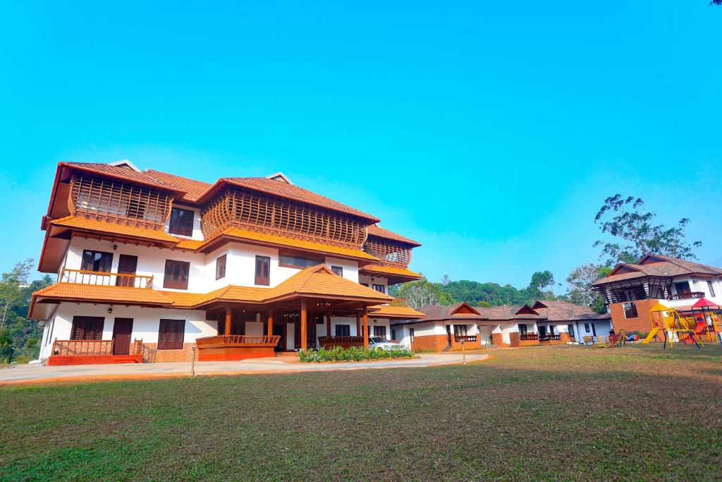 a large building with a grass field in front of it at Heaven Inn Munnar in Munnar