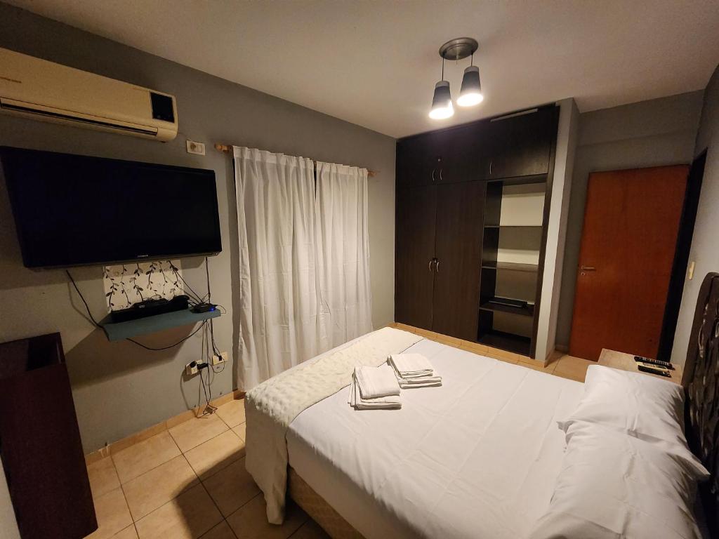 a bedroom with a bed with white sheets and a flat screen tv at At Home CdelU in Concepción del Uruguay