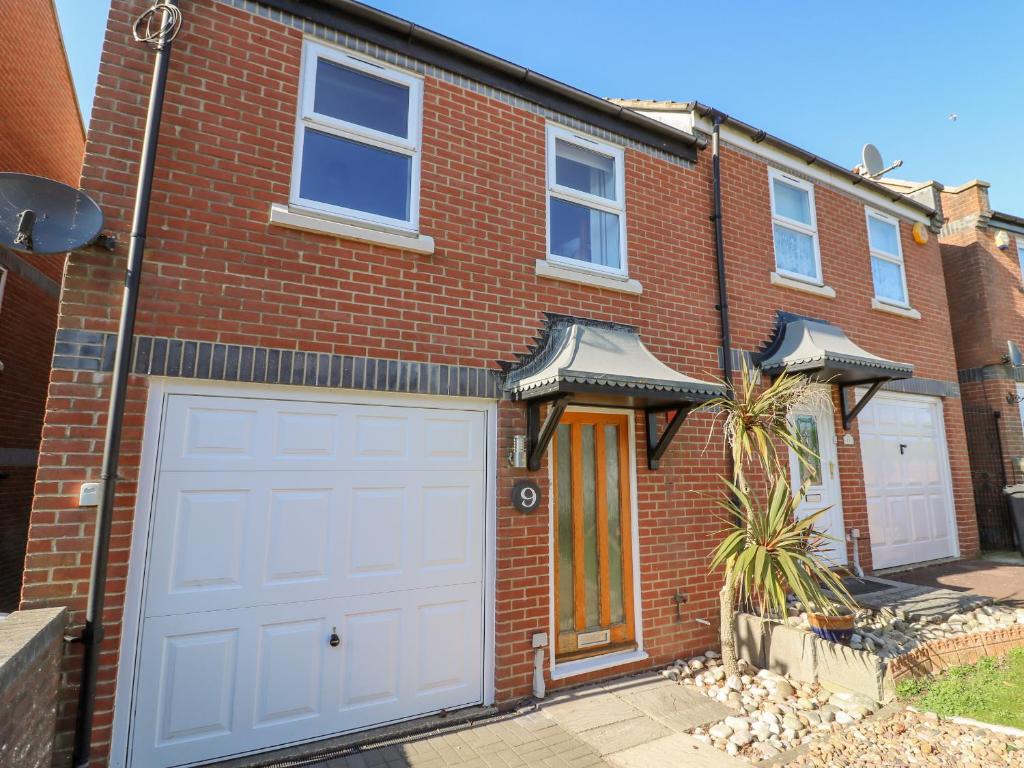 ein rotes Backsteinhaus mit einer weißen Garage in der Unterkunft Sea Pebbles in Weymouth