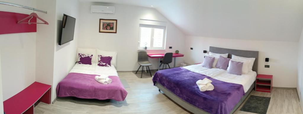 um quarto com 2 camas com lençóis roxos e uma mesa em Rooms Jelak em Velika Gorica