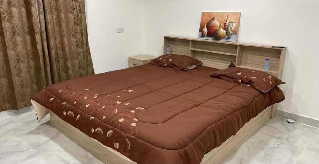 een slaapkamer met een groot bed met bruine lakens en kussens bij Jabal almumsi in Rasīs