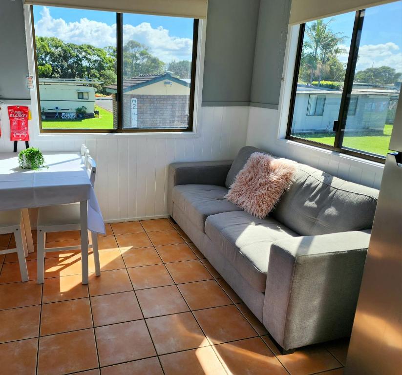 a living room with a couch and a table and windows at Surfrider Caravan Park in Barrack Point