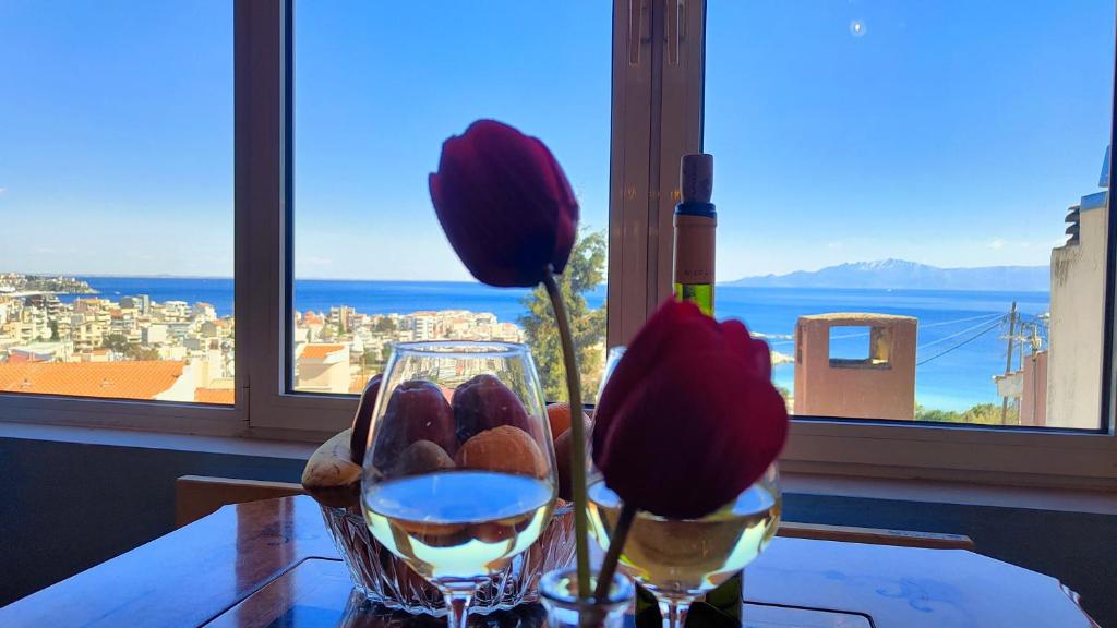 a table with two glasses of wine and a window at Joy View in Kavála
