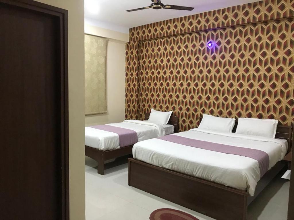a bedroom with two beds and a wall at HOTEL ABINASH in Deoghar