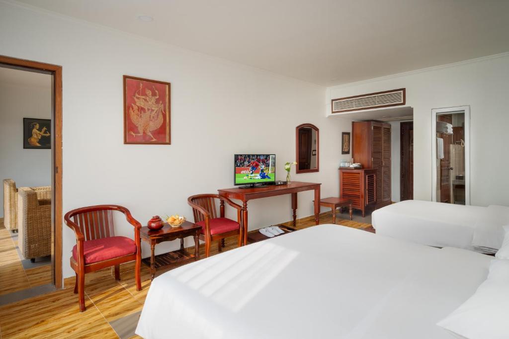 a bedroom with a bed and a desk and chairs at Sala Siem Reap Hotel in Siem Reap