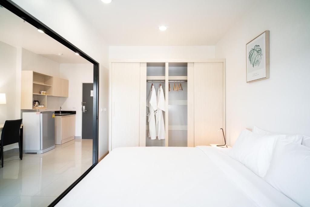 a bedroom with a white bed and a kitchen at KOS Hotel Suvarnabhumi Airport -SHA Extra Plus in Min Buri
