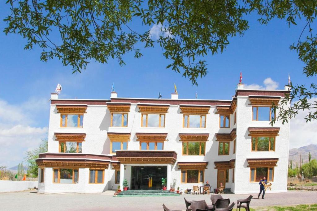 a large white building with tables in front of it at Ratna Hotel Ladakh in Leh