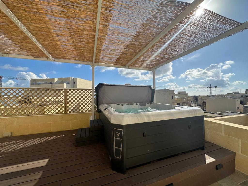 a hot tub on a balcony with a view of a city at Ta Pinu Spa Suite - Luxury Heritage Living in Żebbuġ