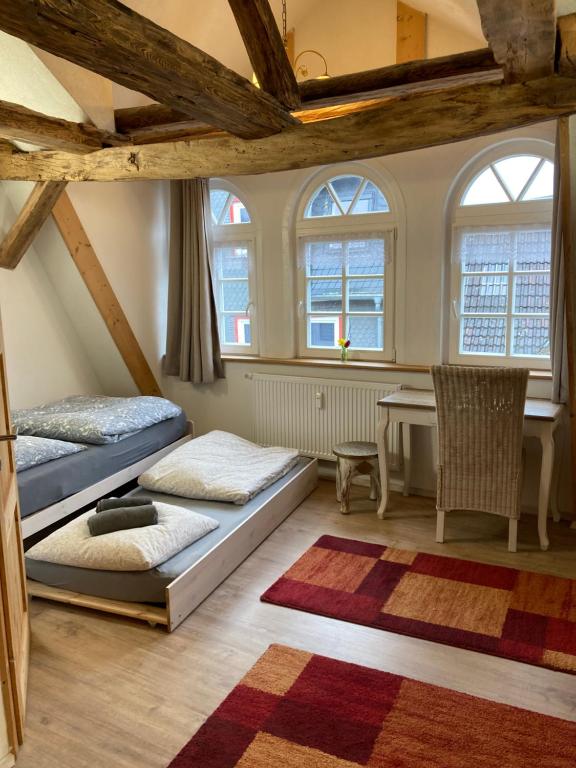 two beds in a room with a table and windows at Gästehaus Keins wie meins in Bad Hersfeld