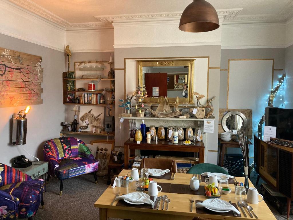 a living room with tables and a couch and a mirror at Kelston Guest House in Weymouth
