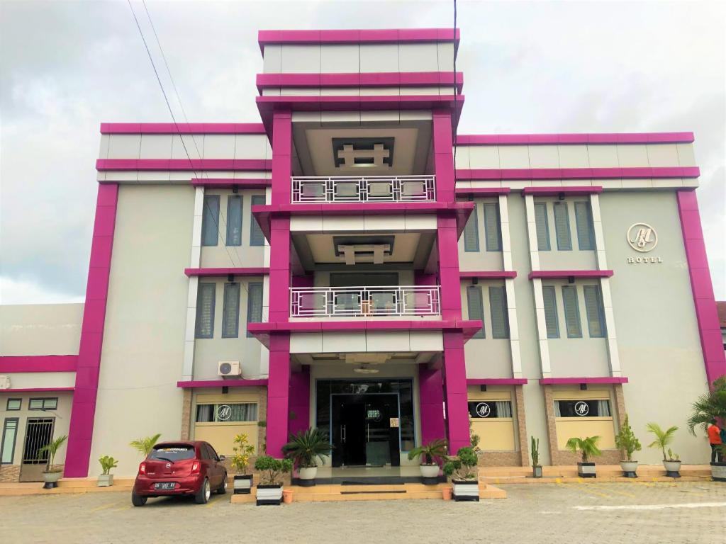 ein rosa und weißes Gebäude mit einem Auto vor dem Haus in der Unterkunft MS Hotel Pinrang Mitra RedDoorz in Pinrang