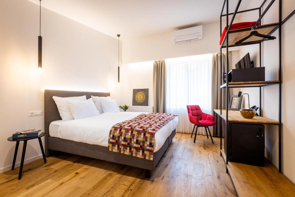 a hotel room with a bed and a red chair at Hotel Slamič Ljubljana in Ljubljana