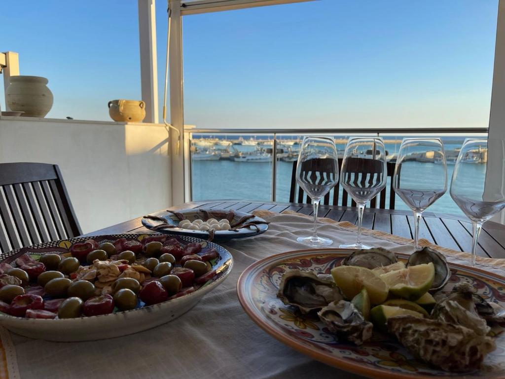 uma mesa com dois pratos de comida e taças de vinho em Casa Marina em Sciacca