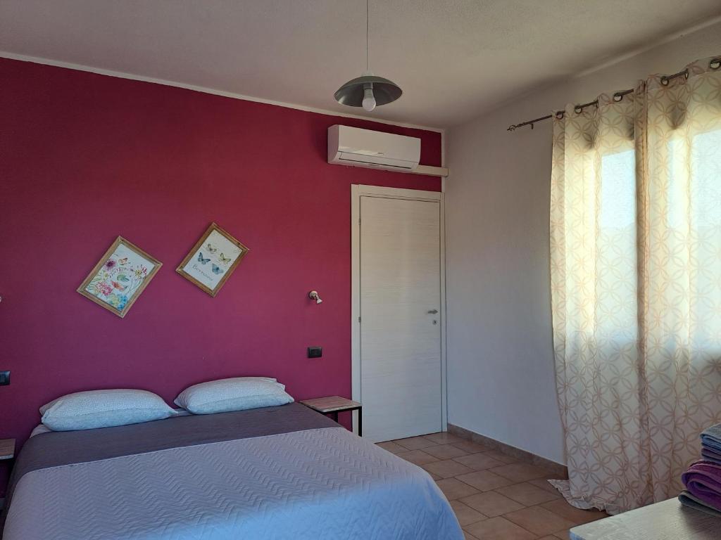SennarioloにあるAlma Bed & Breakfastの赤い壁のベッドルーム1室(ベッド1台付)