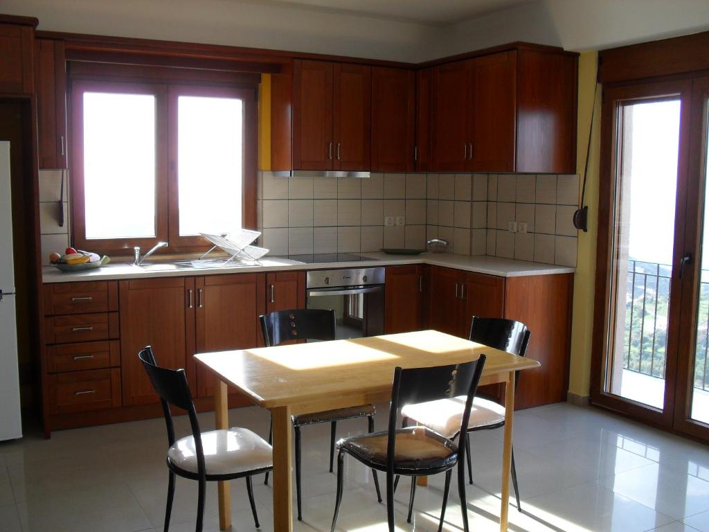 a kitchen with wooden cabinets and a table and chairs at la villa de Rose in Kalymnos
