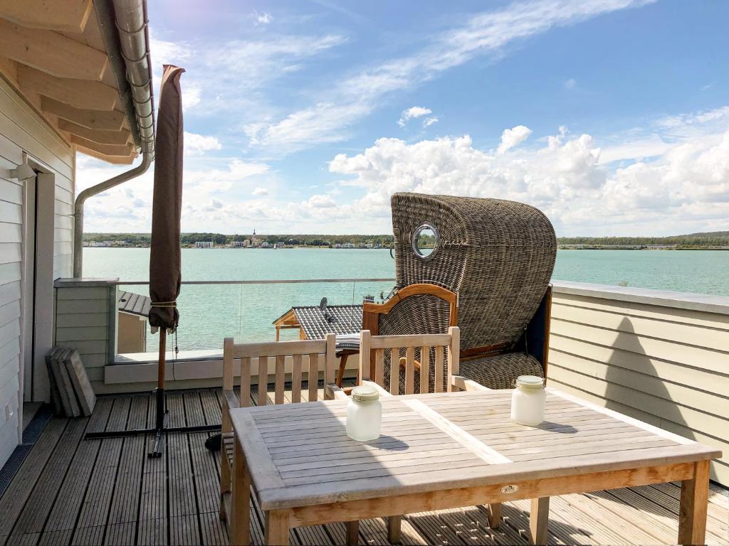 einen Tisch und einen Stuhl auf einer Terrasse mit Blick auf das Wasser in der Unterkunft HAUS IM SCHILF 1 - Ferienwohnungen am Hainer See bei Leipzig in Neukieritzsch